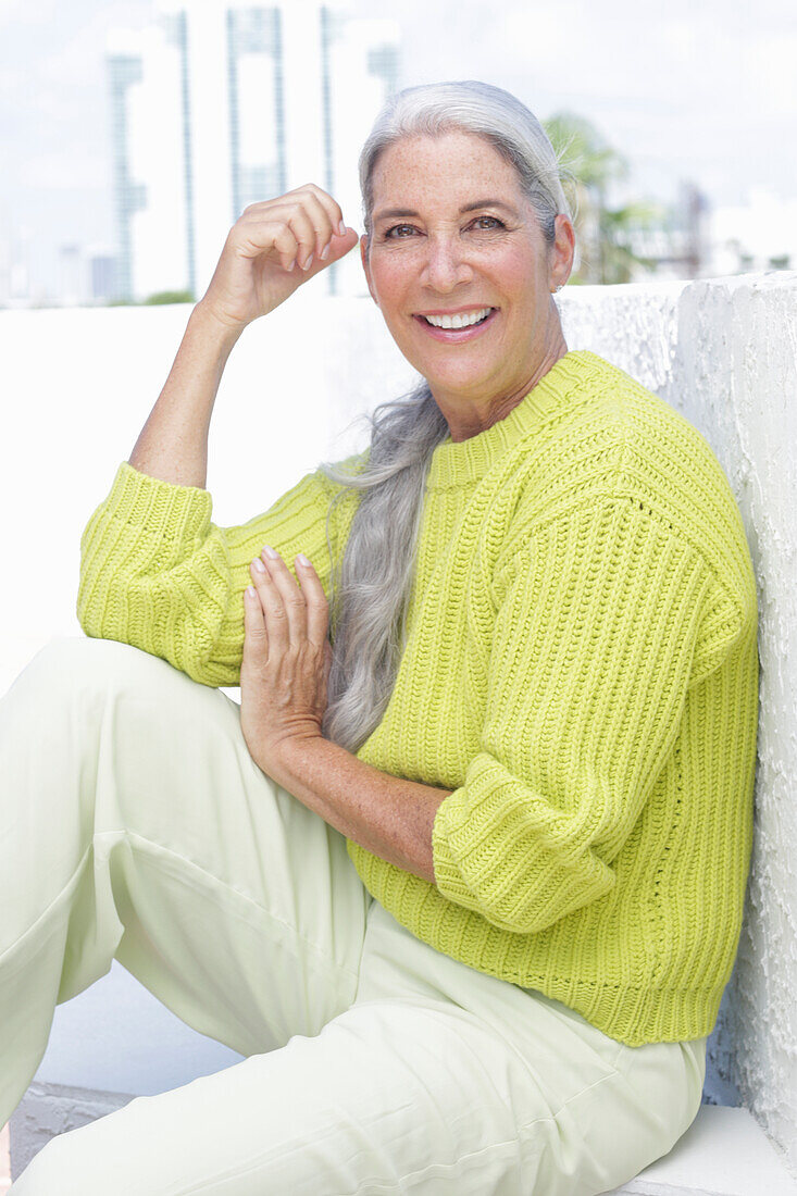 Gray-haired woman in a green-yellow knit sweater and light-colored trousers