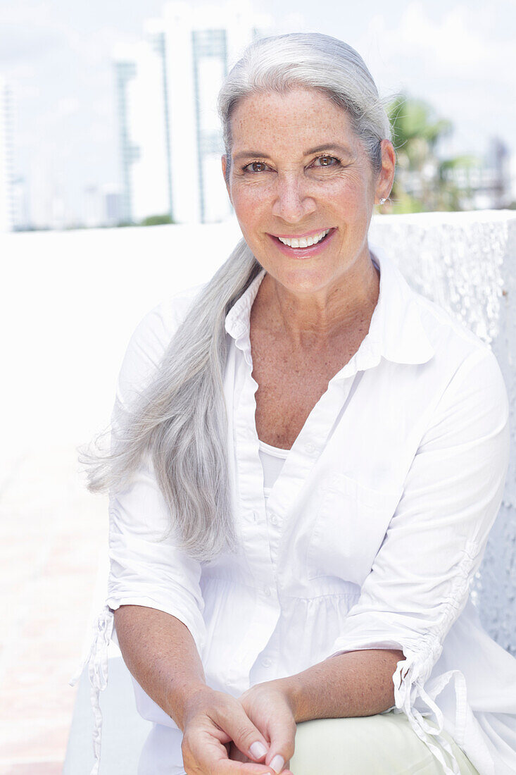 Woman with long gray hair in a white blouse