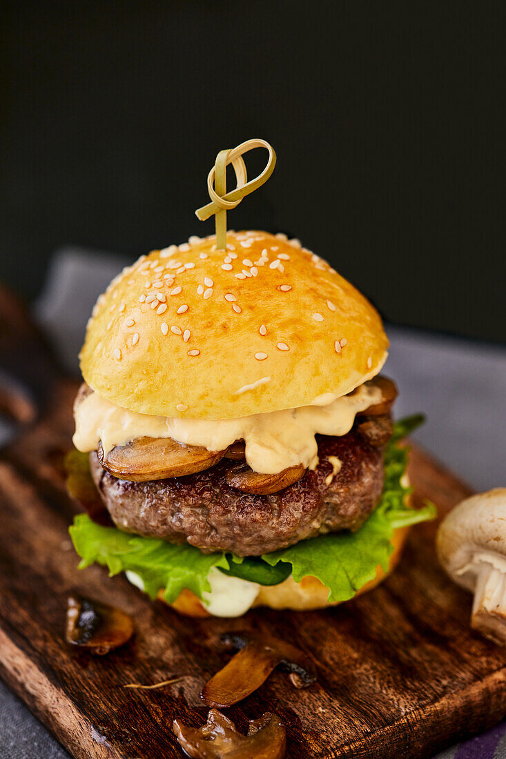 Burger with mushrooms on a wooden cutting board