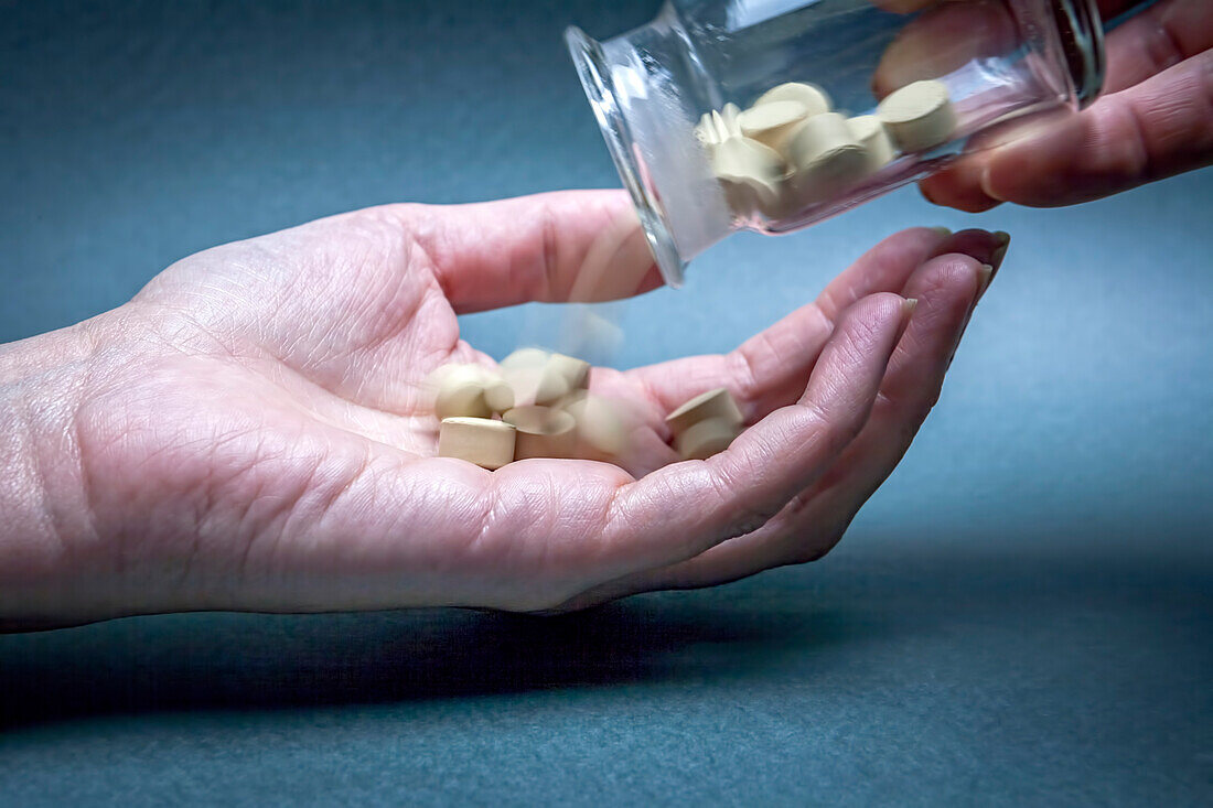 Pills being poured into a woman's hand