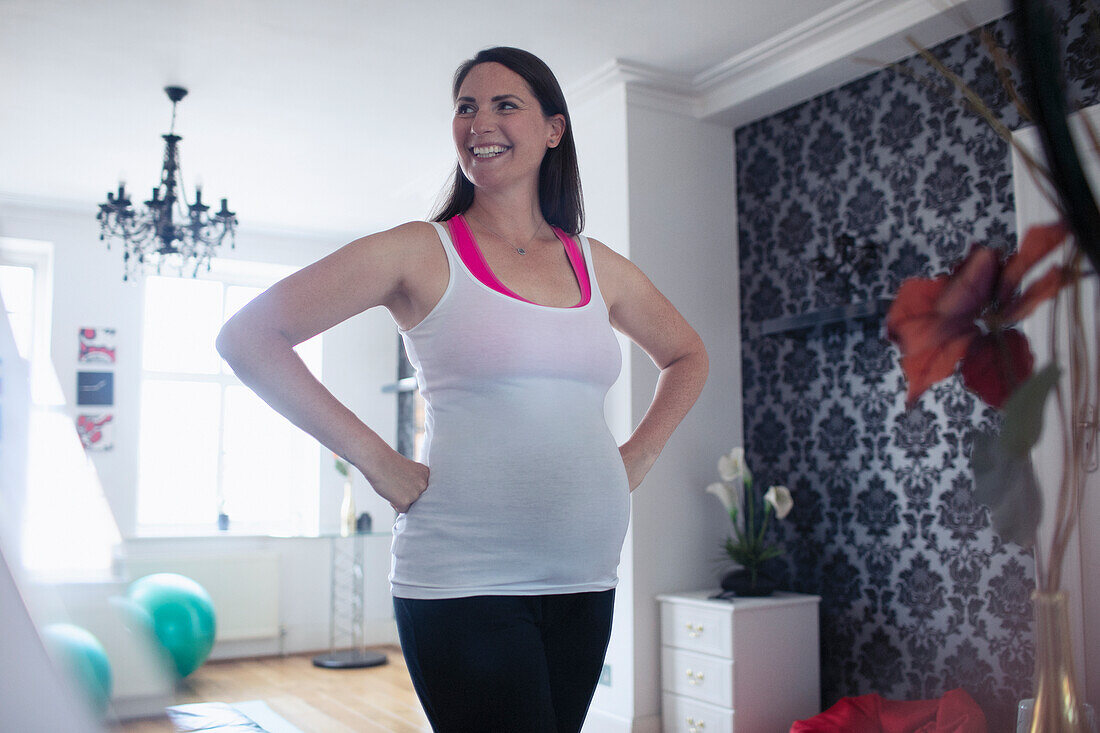 Happy pregnant woman in tank top at home