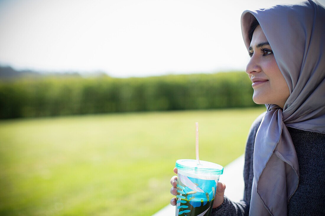 Young woman in headscarf drinking juice