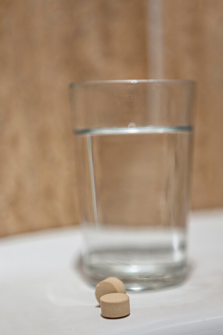 Glass of water and pills in bathroom