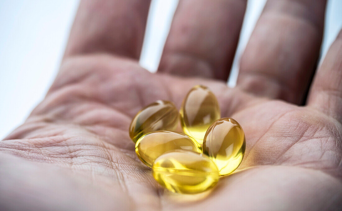 Hand holding several capsules of oil of fish