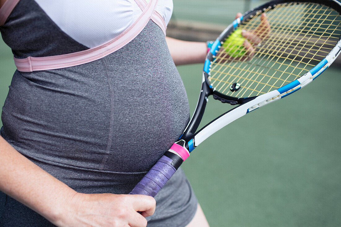 Close up pregnant woman with tennis racket