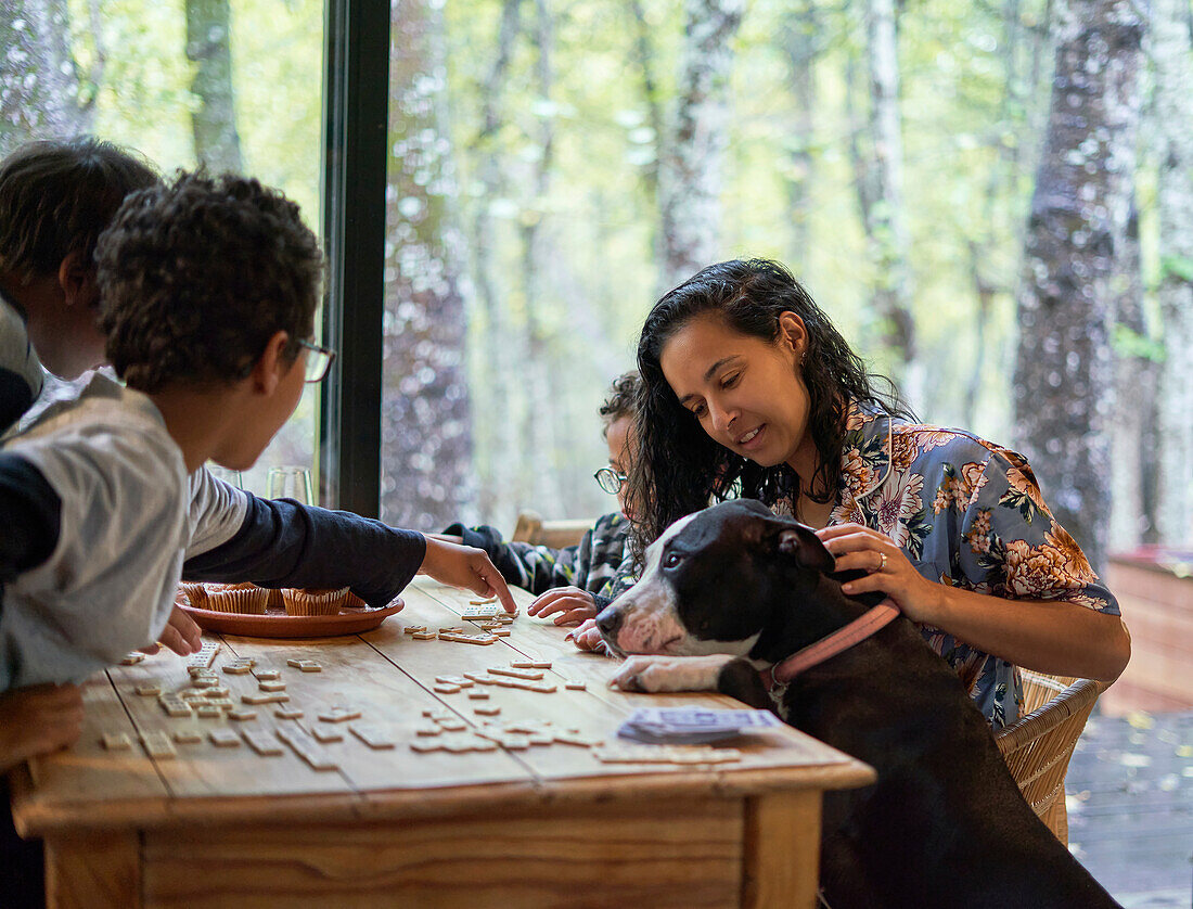 Family with dog playing scrabble at dining table
