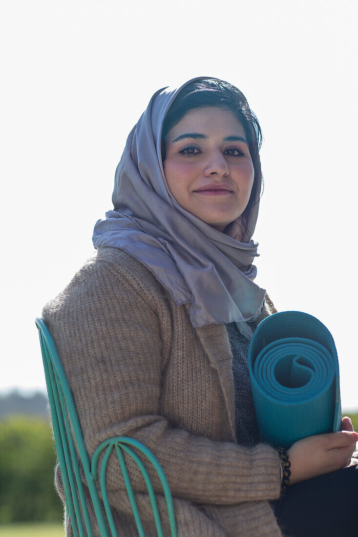 Smiling Muslim woman in hijab with yoga mat