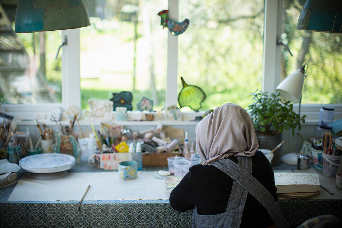 Young female artist in hijab working in art studio