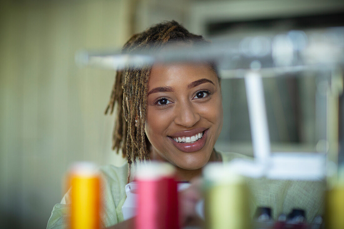 Happy female seamstress behind spools of thread