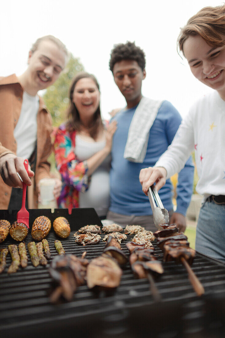 Happy friends barbecuing vegetables at barbecue grill