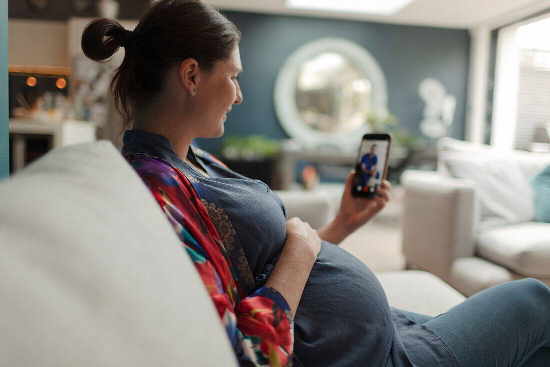 Pregnant woman video chatting with doctor on smart phone