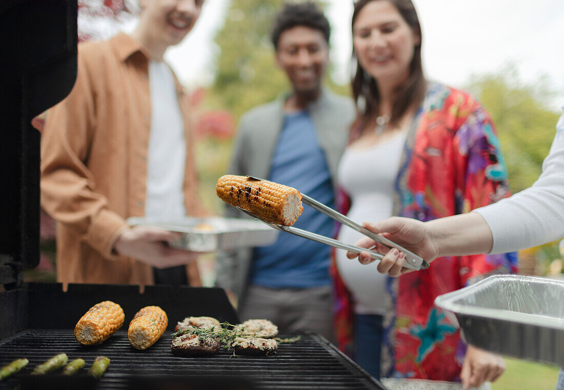 Friends barbecuing corn at barbecue grill