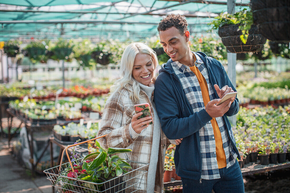 Couple with smart phones shopping in garden shop
