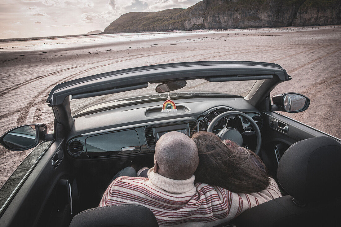 Affectionate couple hugging in convertible on winter beach