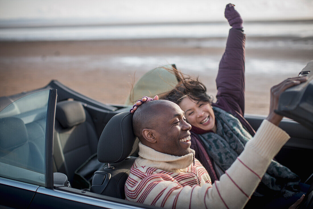 Happy carefree couple in convertible on winter beach