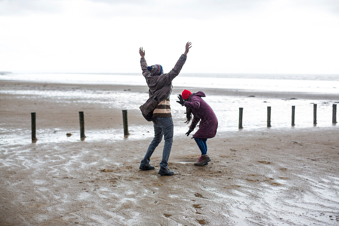 Happy playful couple on wet winter beach