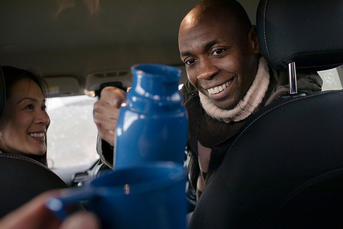 Man pouring coffee from thermos in car