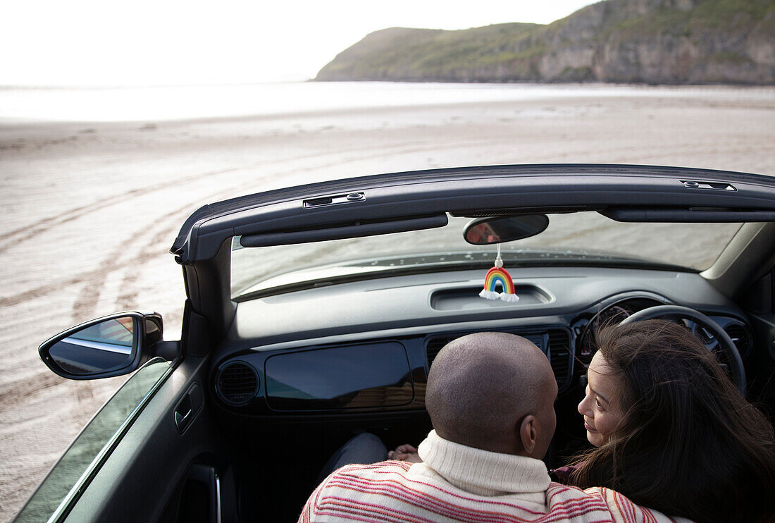 Affectionate couple hugging in convertible on beach