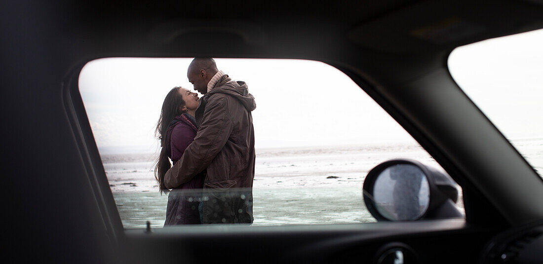 Couple hugging outside car on winter beach