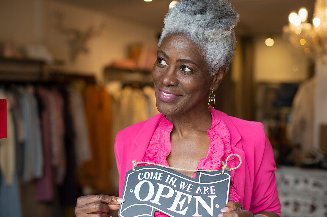 Confident female shop owner with open sign in boutique