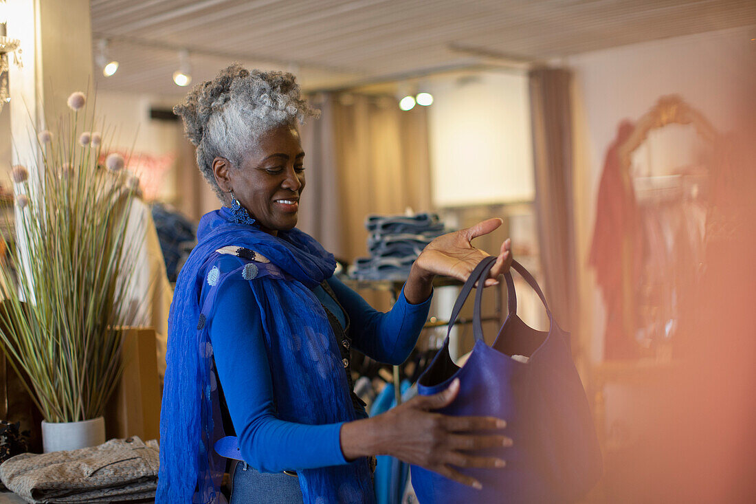 Smiling senior woman looking at handbag in shop