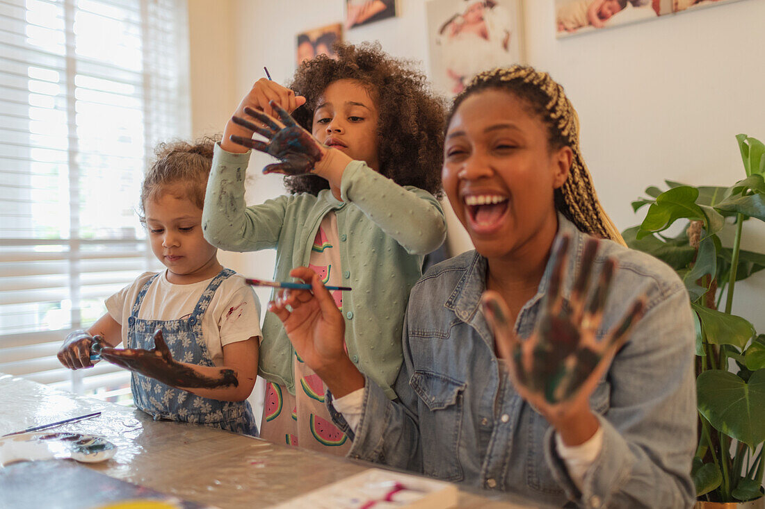 Happy playful mother and daughters finger painting