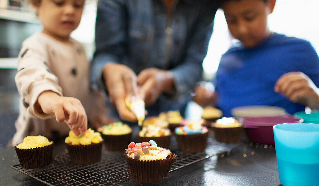 Mother and kids decorating cupcakes