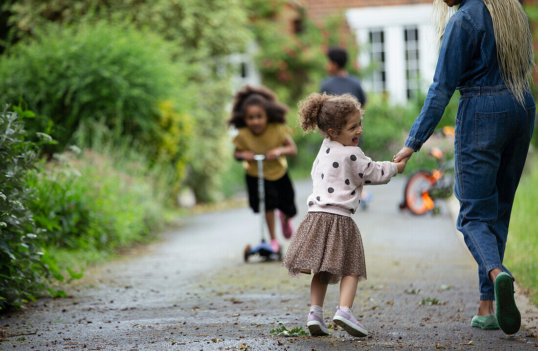 Happy daughter holding hands with mother on driveway