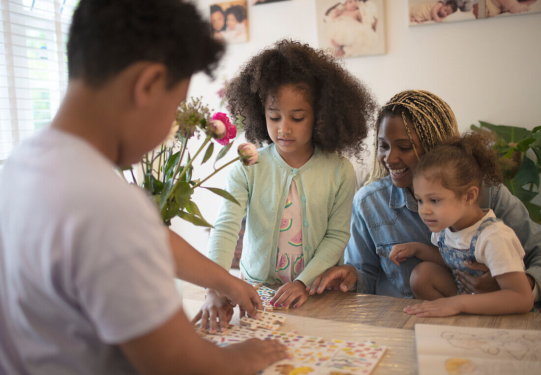 Mother and kids assembling puzzle at table