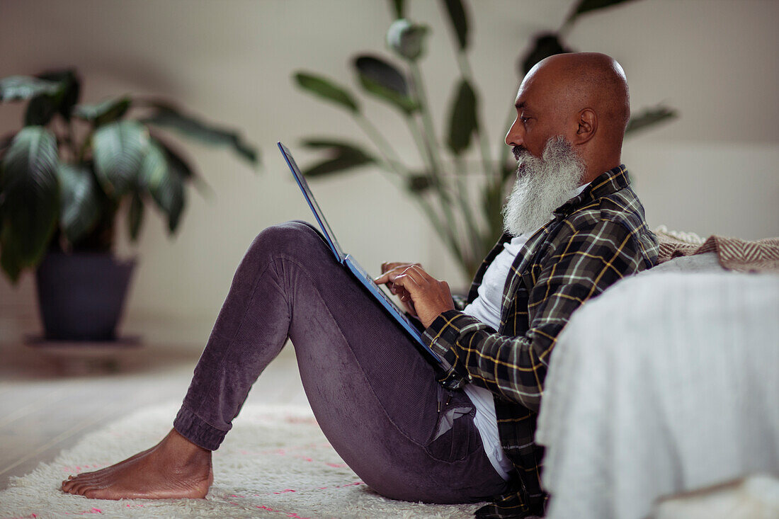 Man with beard using laptop on floor