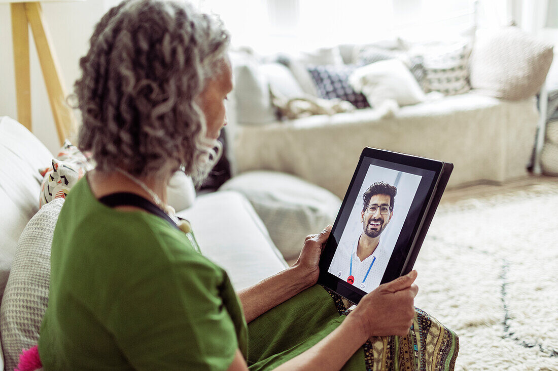 Woman video chatting with doctor on digital tablet screen