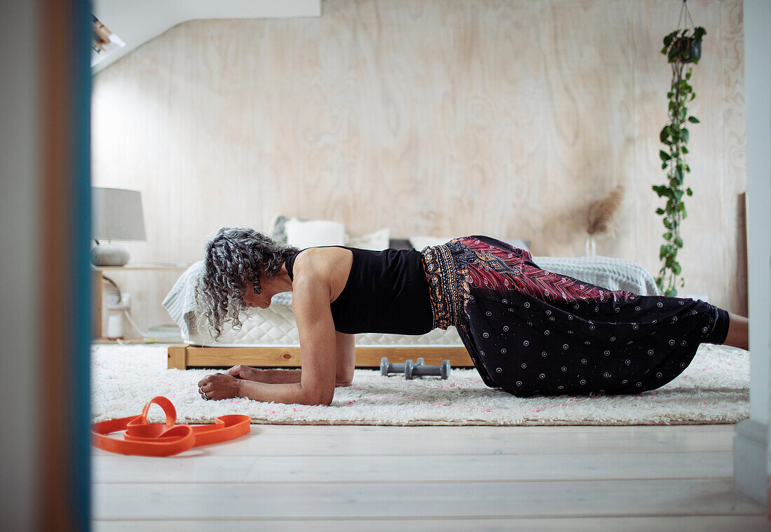 Woman exercising in plank position on bedroom floor