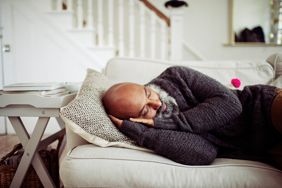 Tired mature man sleeping on living room sofa