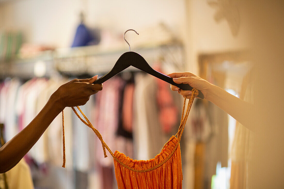 Woman handing dress on hanger to customer in shop