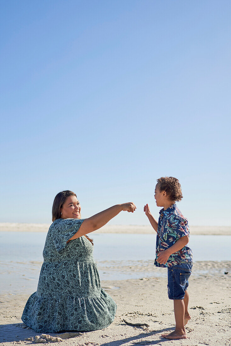 Mother and son fist bumping on beach
