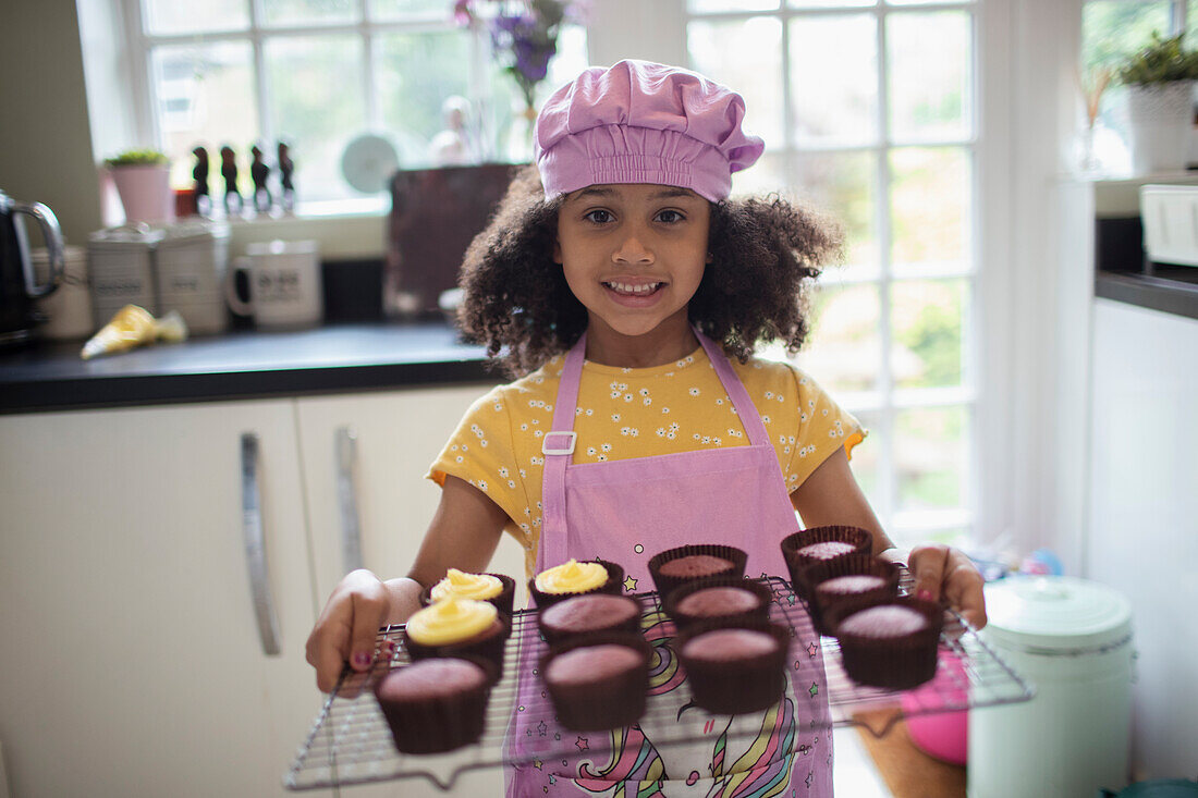 Happy cute girl baking cupcakes on rack