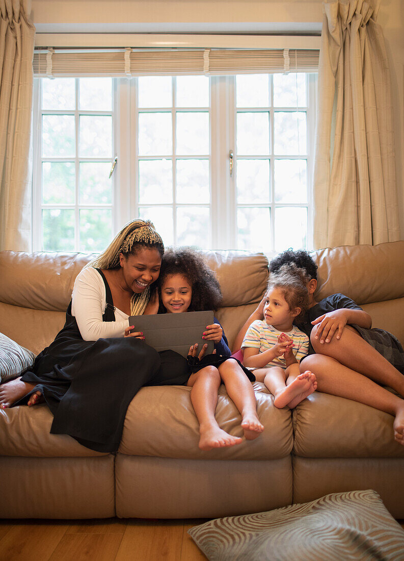 Mother and kids using digital tablet on living room sofa