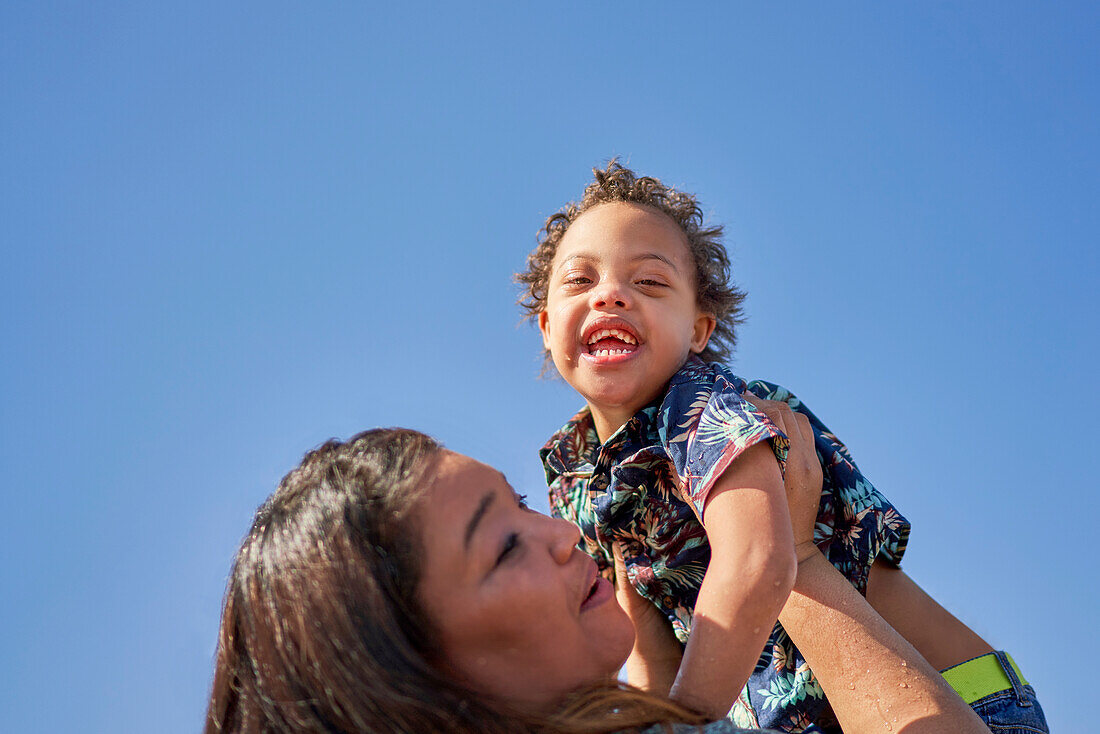 Mother lifting happy, carefree son with Down Syndrome