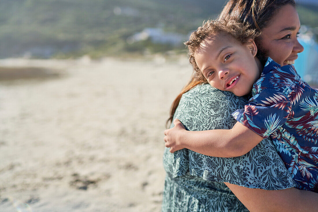 Happy boy with Down Syndrome over shoulder of mother