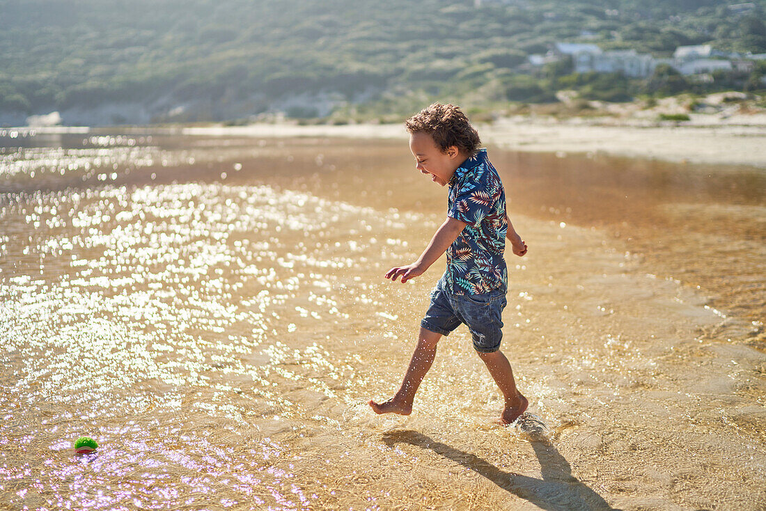 Boy with Down Syndrome running and splashing in ocean surf