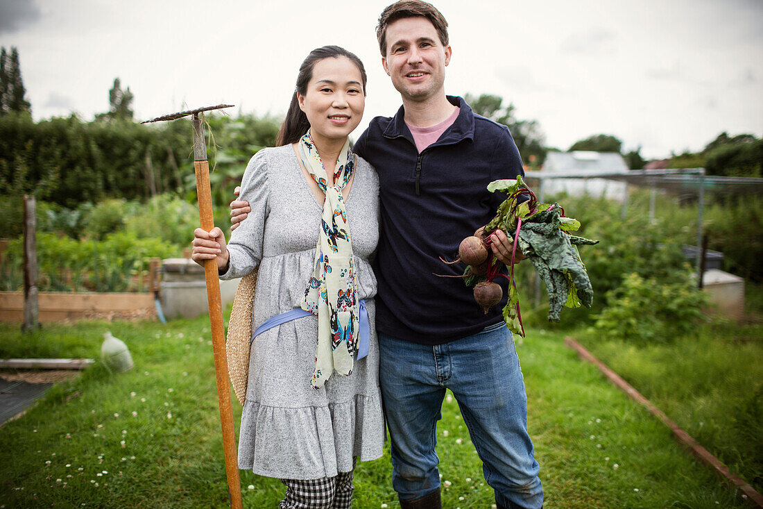 Happy couple with harvested beets in garden