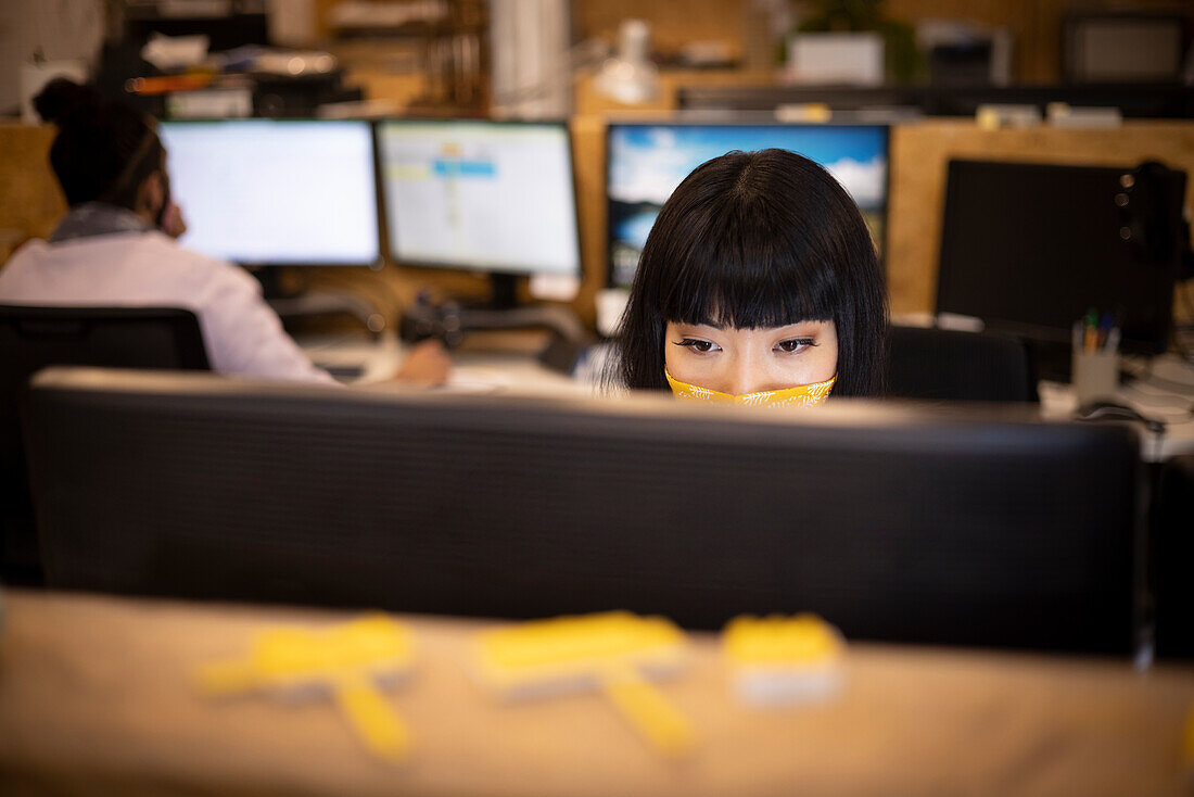 Businesswoman in face mask working at computer in office