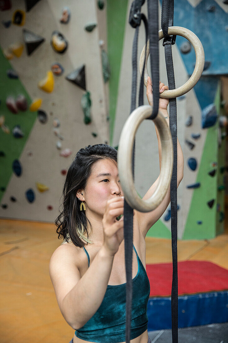Woman exercising at gymnastics rings at rock climbing center