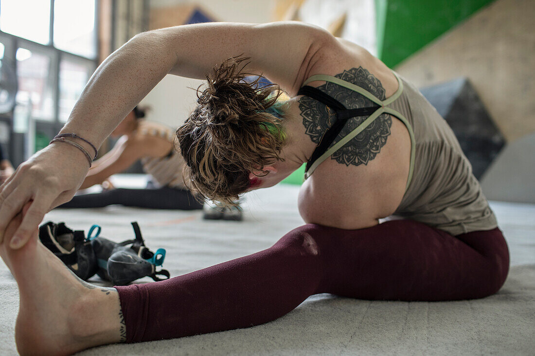 Young female rock climber stretching in climbing gYm