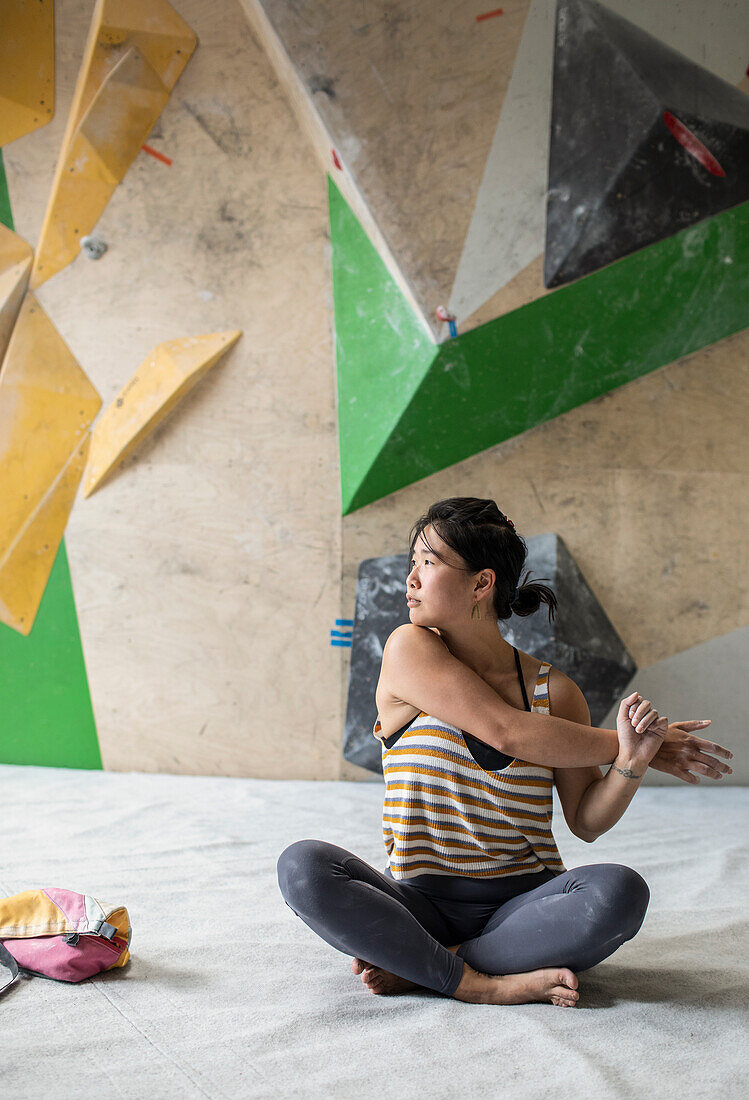 Female rock climber stretching arm in climbing gym
