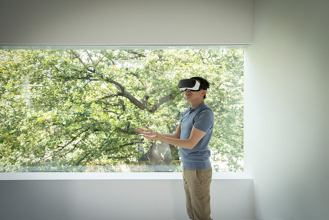 Man using VR headset at window with view of tree