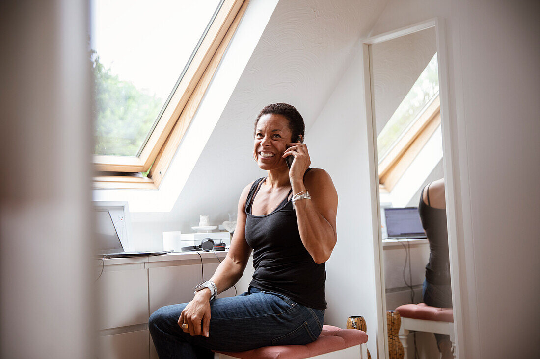 Smiling mature woman talking on smart phone at home