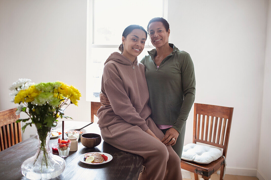 Portrait happy mother and young adult daughter in dining room