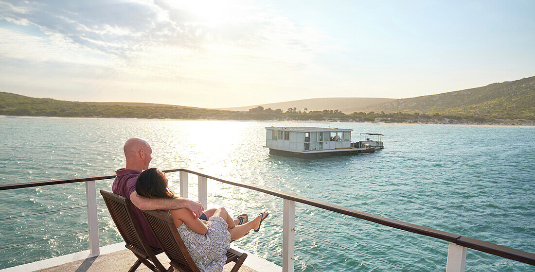 Carefree couple relaxing on houseboat patio on sunny lake