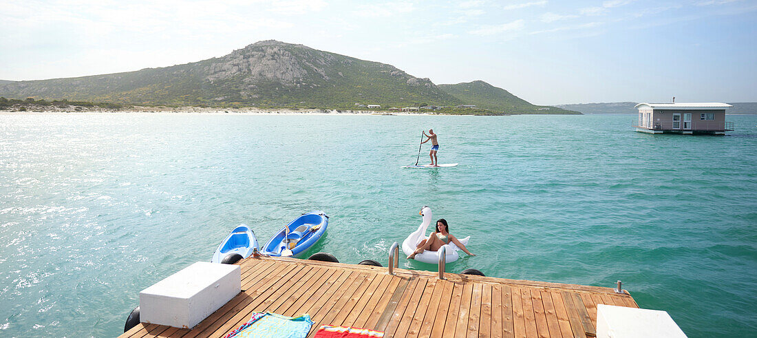 Couple paddleboarding and floating on inflatable raft